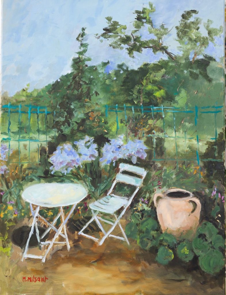 Table ronde et chaise de jardin devant bosquet de fleurs